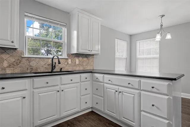 a kitchen with white cabinets and window