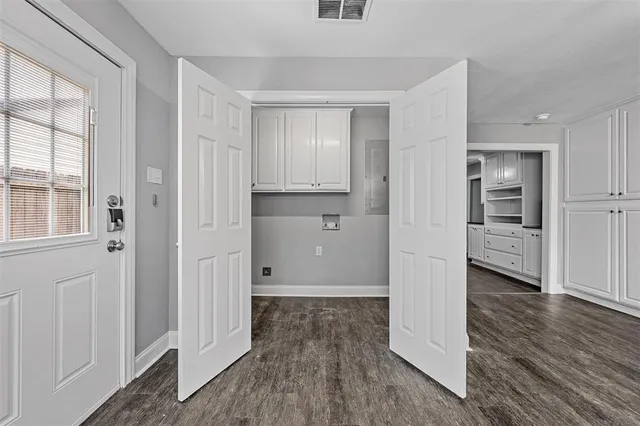 a view of a kitchen from the hallway with wooden floor and a cabinet