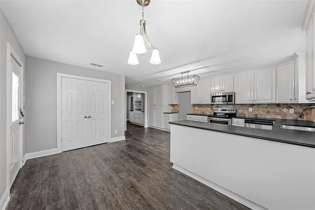 a kitchen with stainless steel appliances granite countertop a sink a stove and a wooden floors