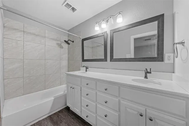 a bathroom with a double vanity sink mirror and bathtub