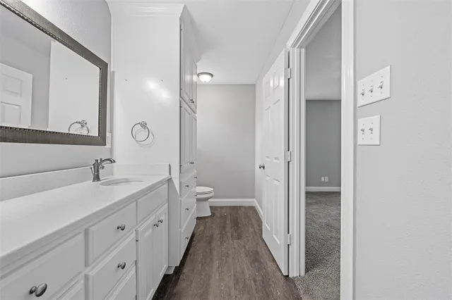 a spacious bathroom with a double vanity sink a toilet and a mirror