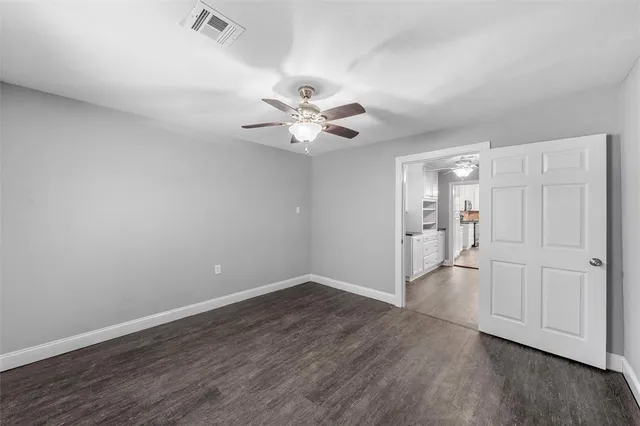 an empty room with wooden floor and a ceiling fan