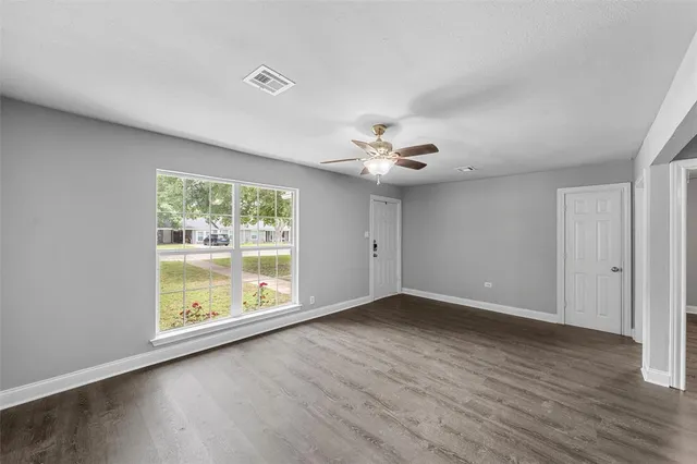 a view of an empty room with a window and wooden floor