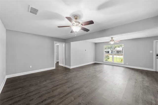 a view of an empty room with window and wooden floor