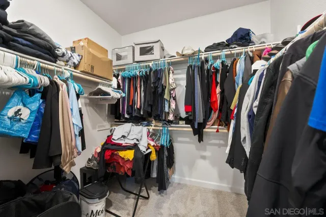 a view of walk in closet with clothes and shoes
