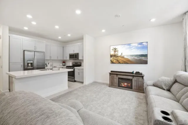 a living room with furniture a flat screen tv and kitchen view