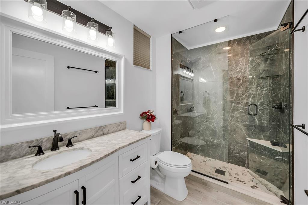 4620 St Croix Lane, Unit 918 Naples, FL 34109 - Photo 14 of 43 a bathroom with a granite countertop sink a toilet and shower