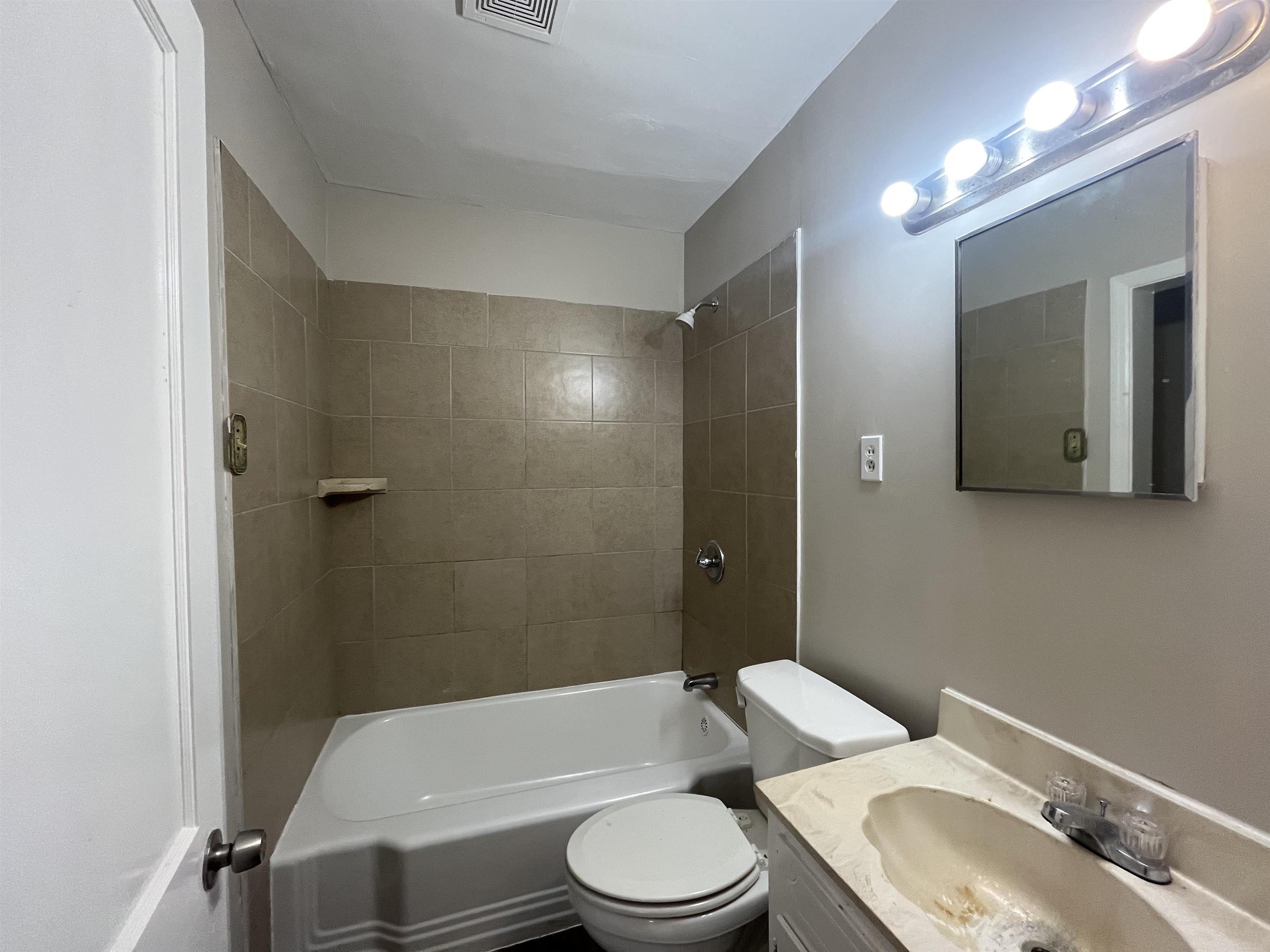 1362 Springdale Street Memphis, TN 38108 - Photo 9 of 16 a white toilet and tub sitting next to a bathroom sink