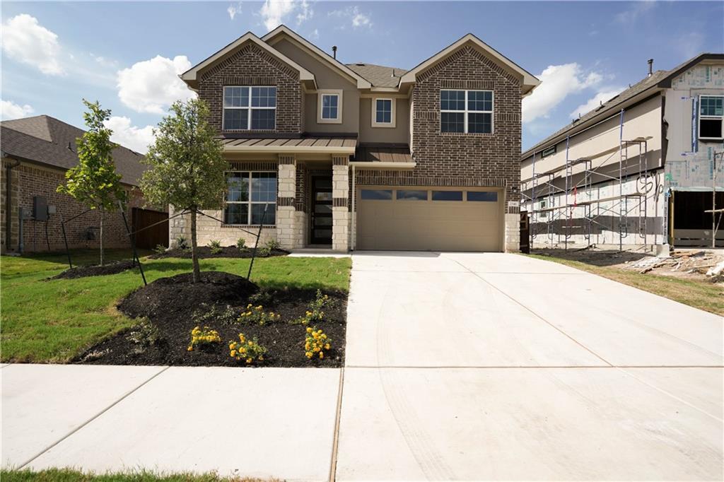 View of front of property with a standing seam roof, brick siding, a metal roof, and driveway