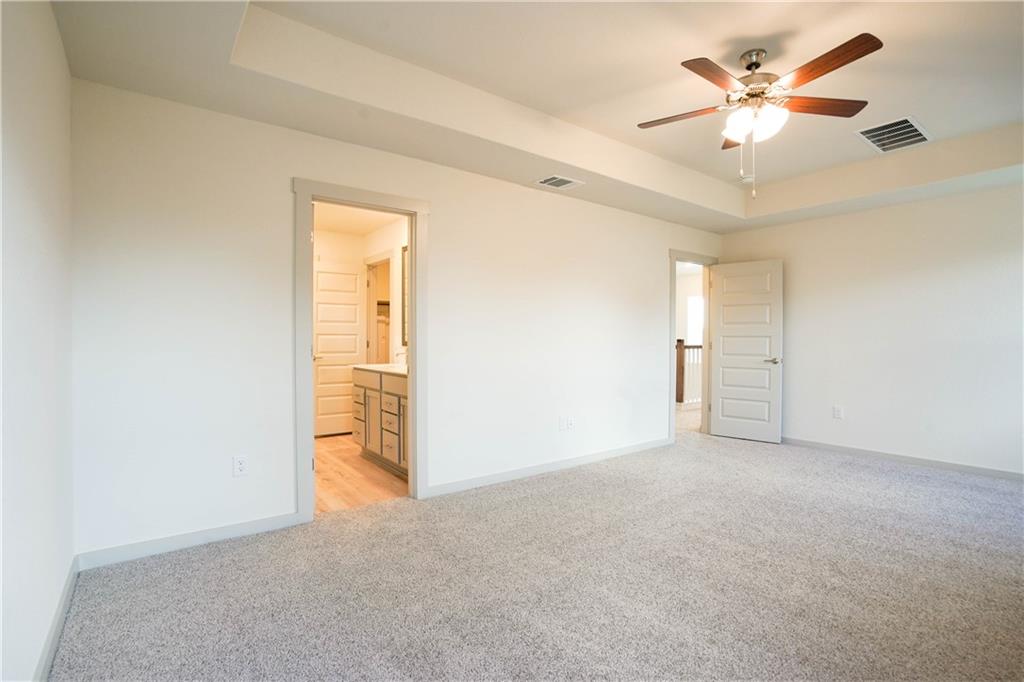 2341 Gabriels Horn Road Leander, TX 78641 - Photo 12 of 20 Unfurnished bedroom featuring a tray ceiling, light colored carpet, ceiling fan, and ensuite bathroom