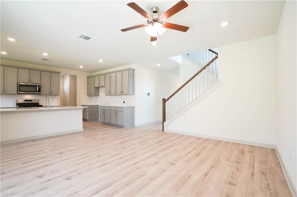 2341 Gabriels Horn Road Leander, TX 78641 - Photo 19 of 20 Kitchen with gray cabinetry, open floor plan, appliances with stainless steel finishes, recessed lighting, and light wood-style floors