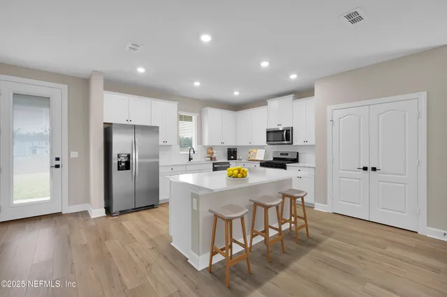 a kitchen with stainless steel appliances a refrigerator a stove a sink dishwasher and a refrigerator with wooden floor