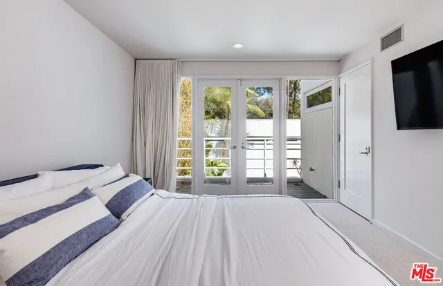 a bedroom with a bed and large windows