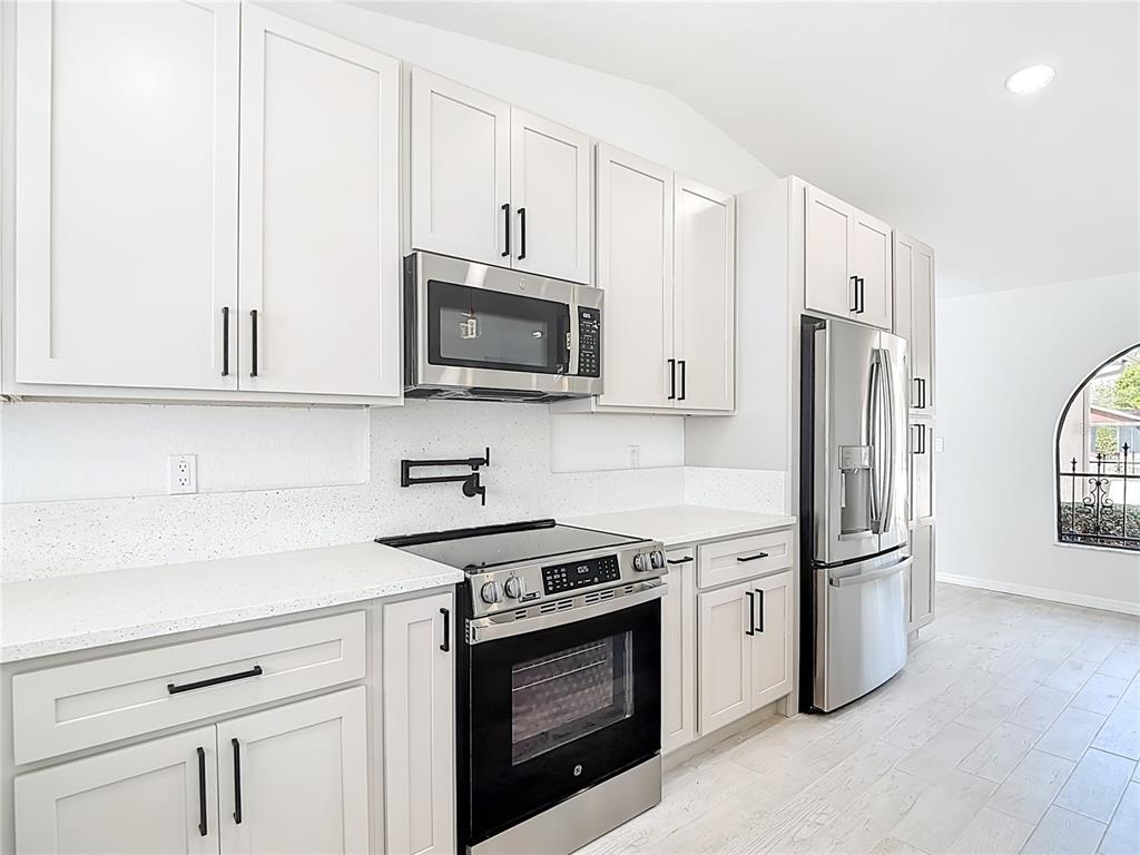 7478 Dundee Way Weeki Wachee, FL 34613 - Photo 18 of 52 a kitchen with stainless steel appliances white cabinets and a stove top oven