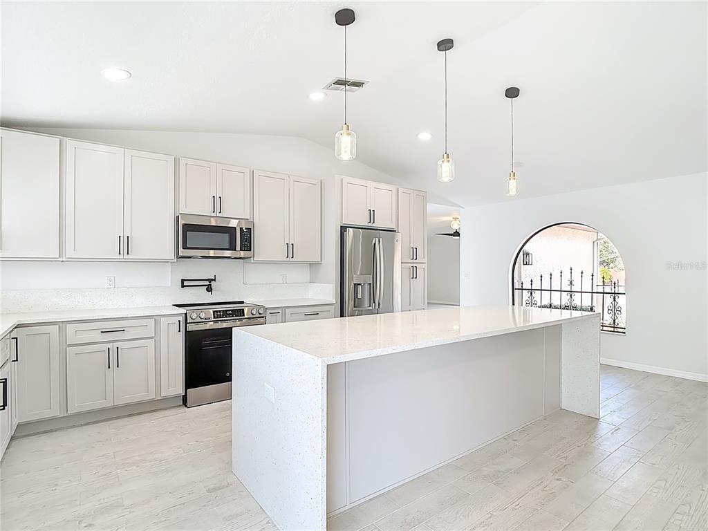 7478 Dundee Way Weeki Wachee, FL 34613 - Photo 22 of 52 a kitchen with stainless steel appliances granite countertop a stove a sink dishwasher a refrigerator and a dining table with wooden floor