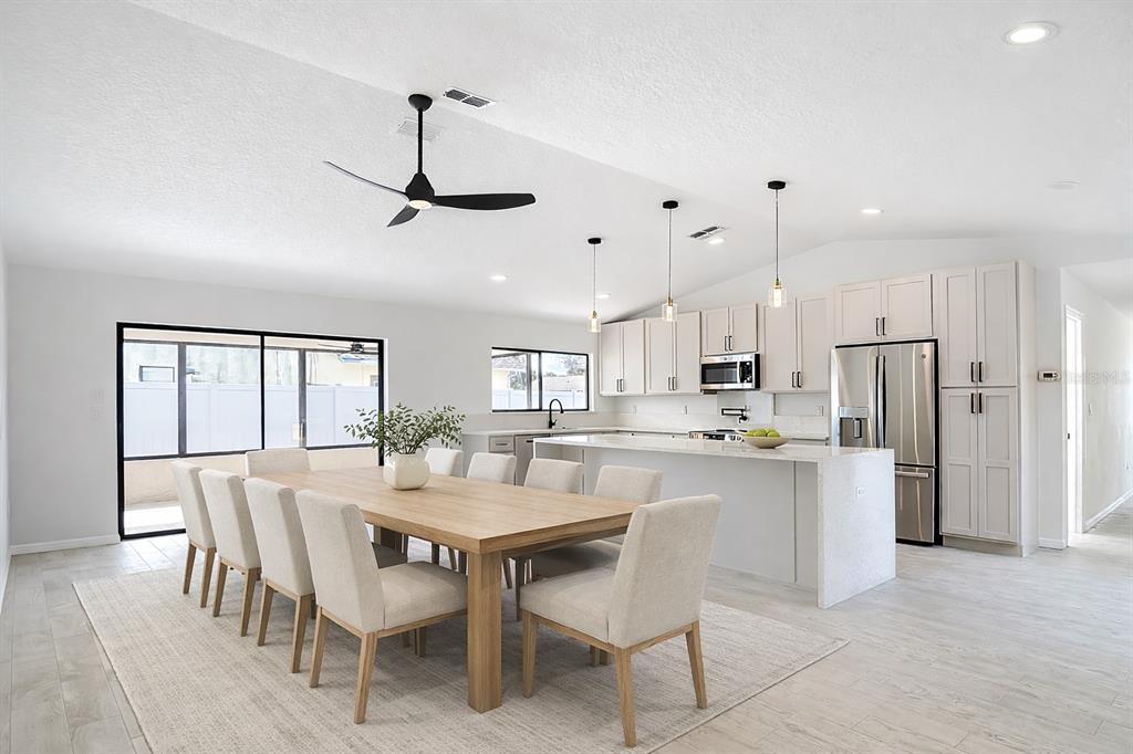 7478 Dundee Way Weeki Wachee, FL 34613 - Photo 24 of 52 a kitchen with a dining table chairs wooden floor and windows