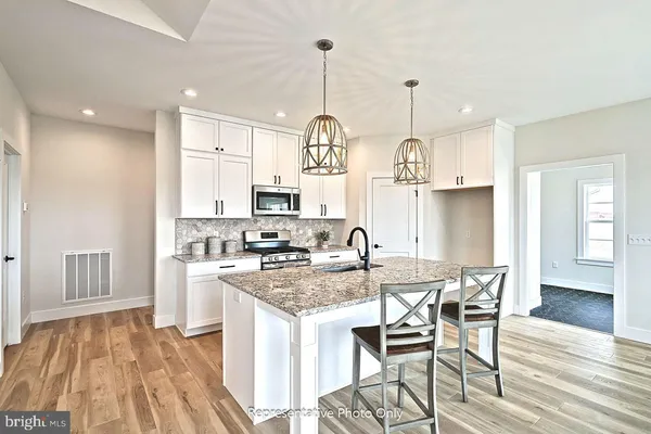 a kitchen with stainless steel appliances granite countertop a kitchen island a stove a table and chairs in it