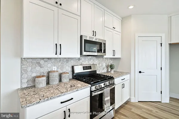 a kitchen with stainless steel appliances granite countertop white cabinets and a stove