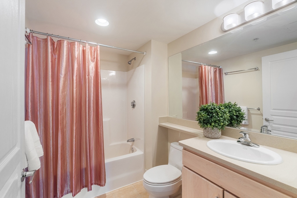 4 Repton Place, Unit 4213 Watertown, MA 02472 - Photo 14 of 19 a bathroom with a sink toilet a large mirror and shower curtain