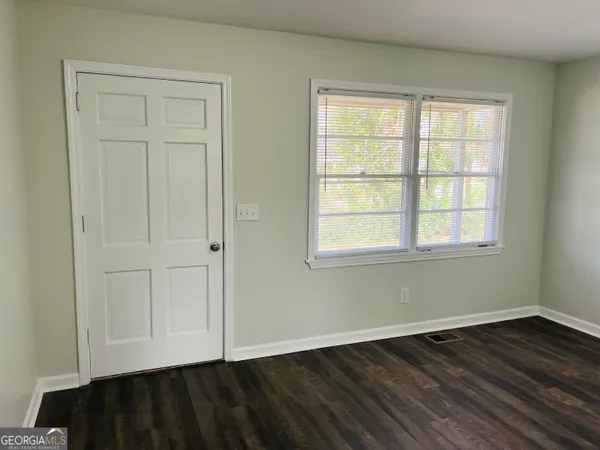 an empty room with wooden floor closet and windows