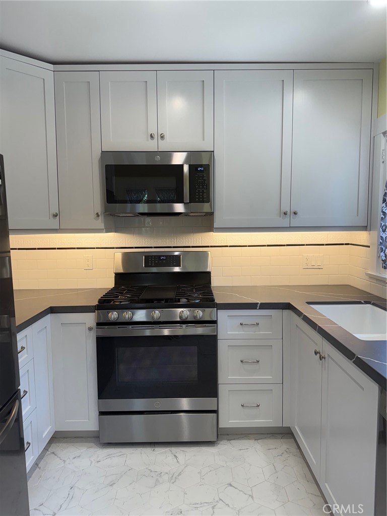 297 Garfield Avenue Pasadena, CA 91101 - Photo 10 of 28 a kitchen with granite countertop white cabinets and stainless steel appliances