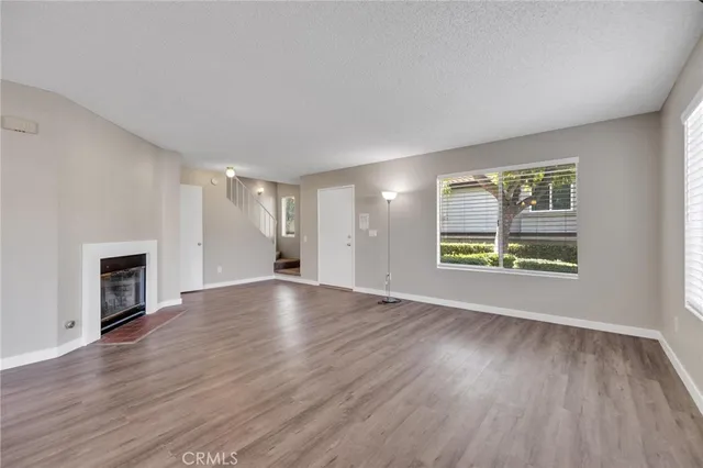 an empty room with wooden floor fireplace and windows