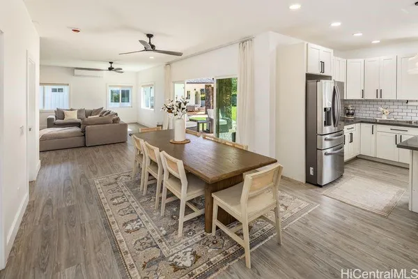 a kitchen with stainless steel appliances kitchen island granite countertop a dining table chairs refrigerator sink and cabinets