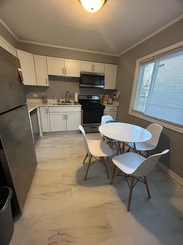 a kitchen with stainless steel appliances a dining table chairs and a refrigerator