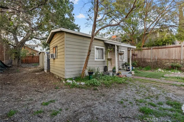 a backyard of a house with plants and large tree