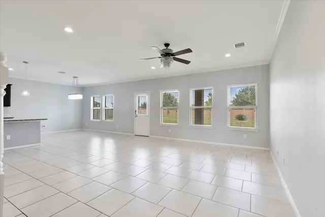 an empty room with windows and chandelier fan