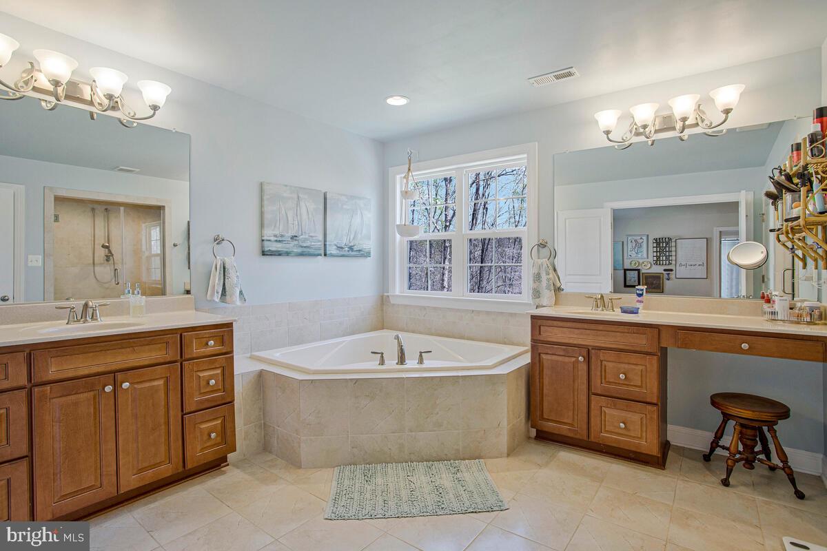 54 Simmons Ridge Road Prince Frederick, MD 20678 - Photo 34 of 55 a spacious bathroom with a tub a double vanity sink a window a mirror and