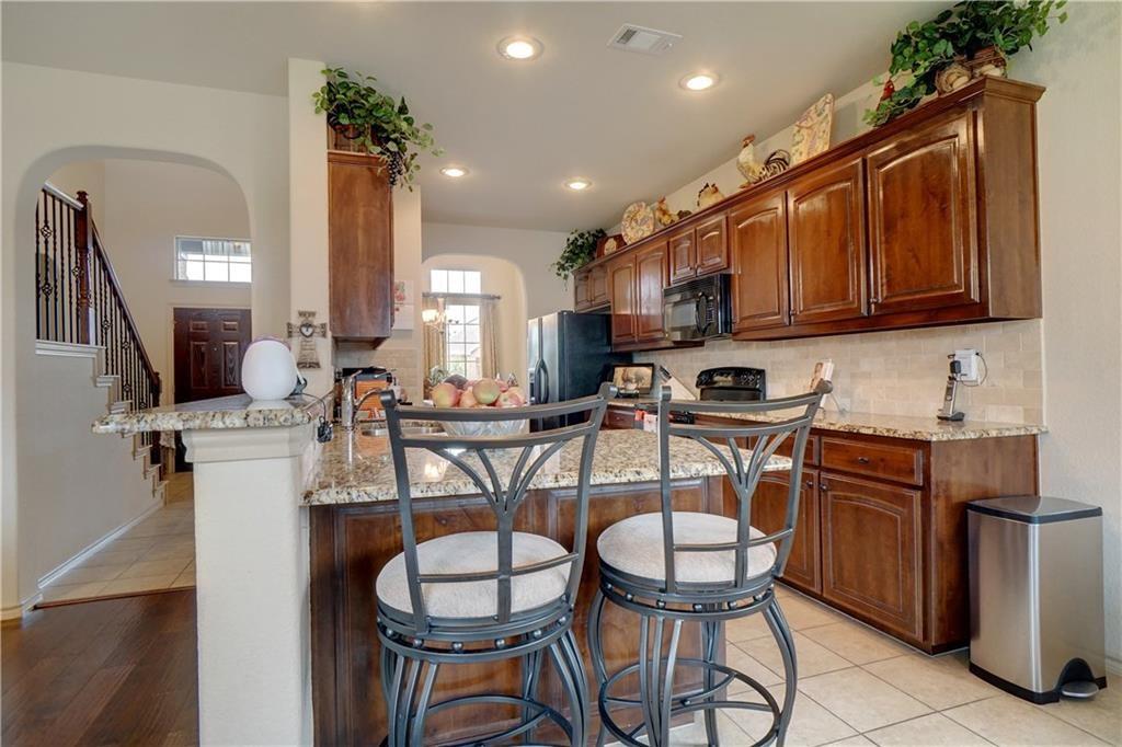13212 Larks View Point Fort Worth, TX 76244 - Photo 12 of 36 a kitchen with stainless steel appliances granite countertop a sink a stove a refrigerator cabinets and chairs