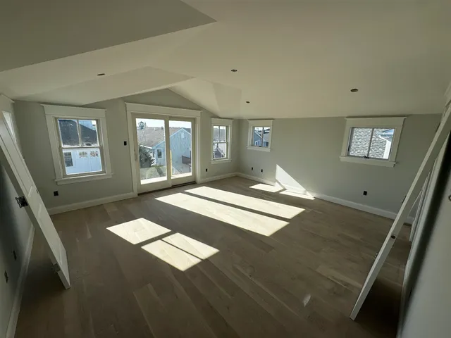 a view of an empty room with window and wooden floor