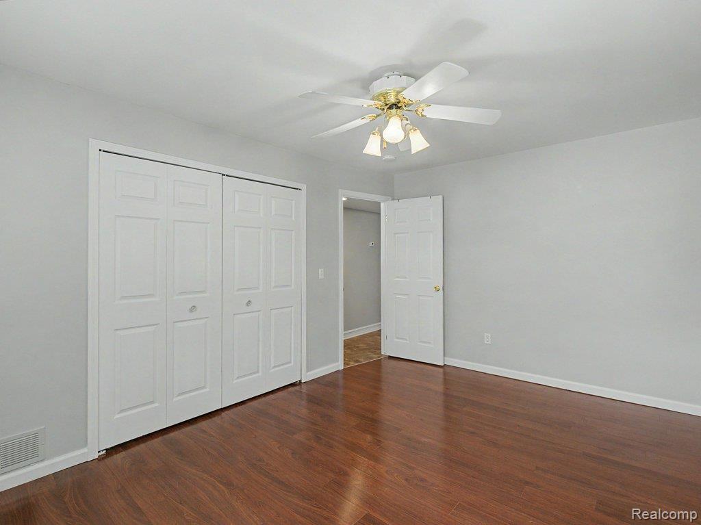 1974 Klingensmith Road, Unit 4 Bloomfield Hills, MI 48302 - Photo 14 of 35 Room featuring wood-finish flooring, light gray walls, a white ceiling fan with integrated lighting, and white bi-fold closet doors