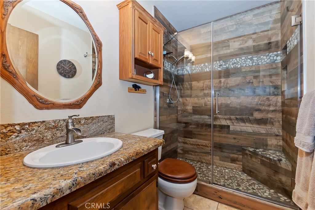1100 Arbula Drive Crestline, CA 92325 - Photo 27 of 50 a bathroom with a granite countertop sink a toilet and a mirror
