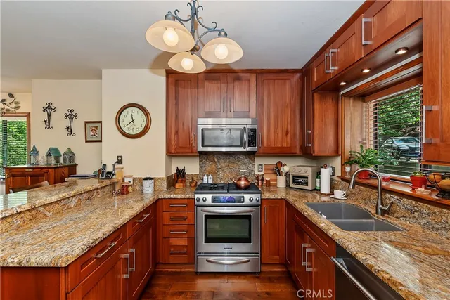 a kitchen with stainless steel appliances granite countertop a sink a stove top oven a clock and cabinets
