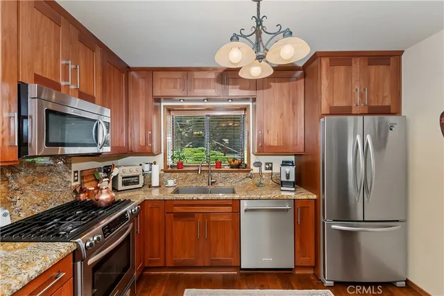 a kitchen with stainless steel appliances granite countertop a refrigerator a stove top oven a sink and dishwasher
