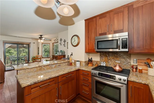 a kitchen with stainless steel appliances granite countertop a stove a microwave a sink and dishwasher with wooden cabinets