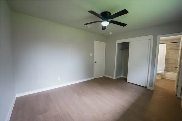 an empty room with wooden floor and a ceiling fan