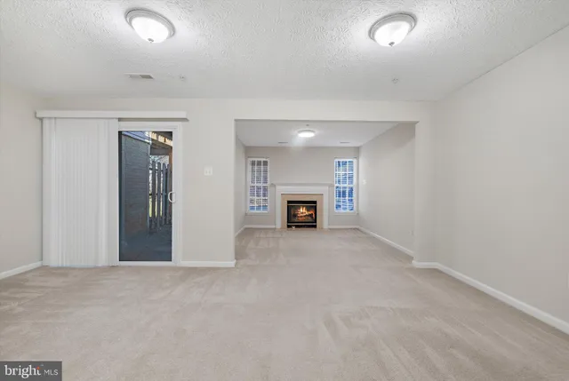 a view of an empty room with a fireplace and a window