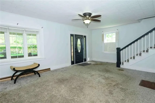 a view of an empty room with window and hardwood floor