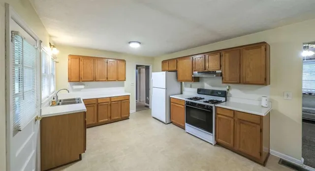a kitchen with granite countertop a stove top oven sink and cabinets