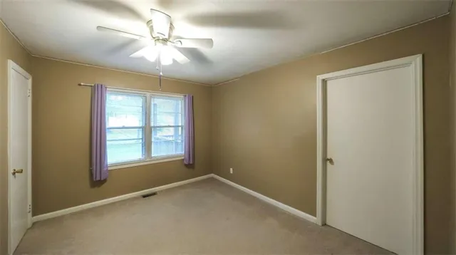 an empty room with fan and windows
