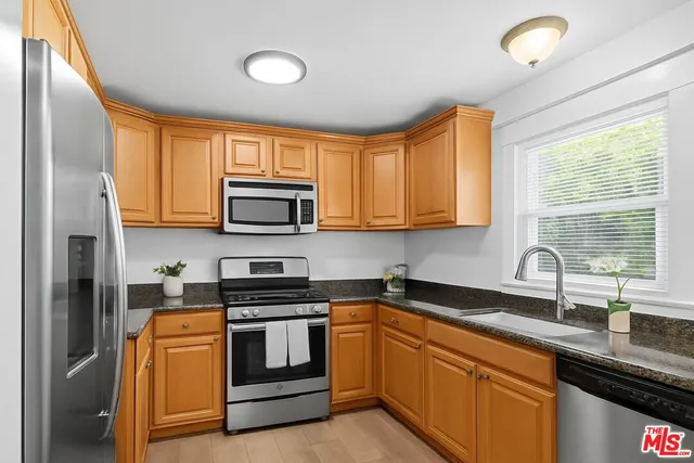 a kitchen with granite countertop a sink stainless steel appliances and cabinets