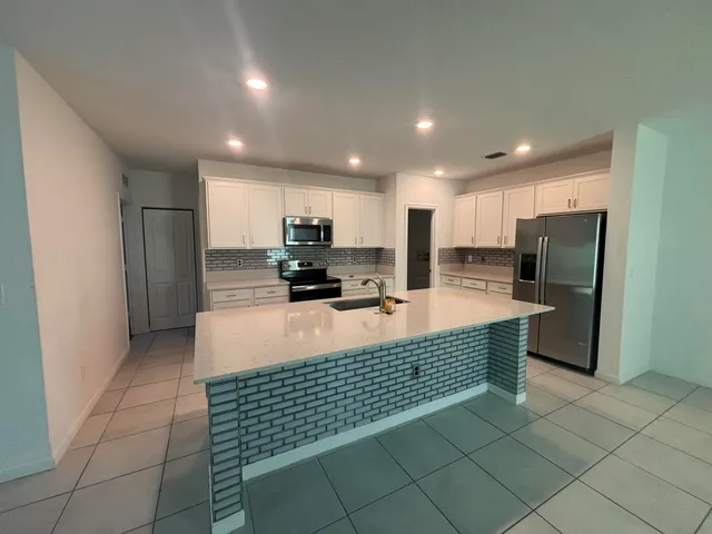 a large kitchen with a large counter top stainless steel appliances and cabinets