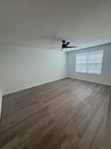 an empty room with wooden floor cabinet and windows
