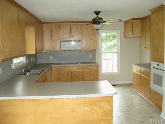 Large kitchen with lots of countertop space, ceiling fan, built in microwave, with cook top, separate oven & pantry