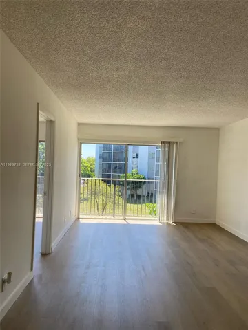 an empty room with floor to ceiling window and wooden floor