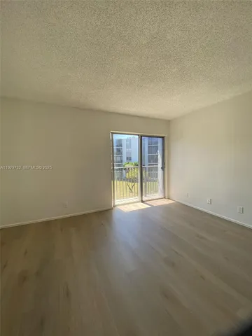 an empty room with wooden floor and fan
