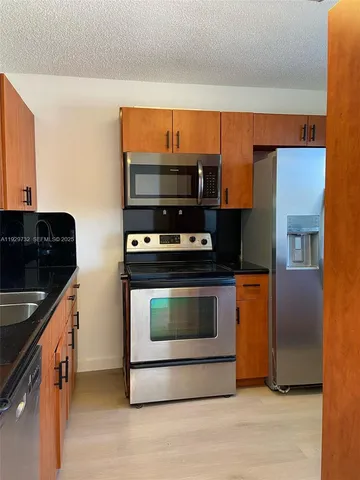 a kitchen with stainless steel appliances a stove a microwave and a sink